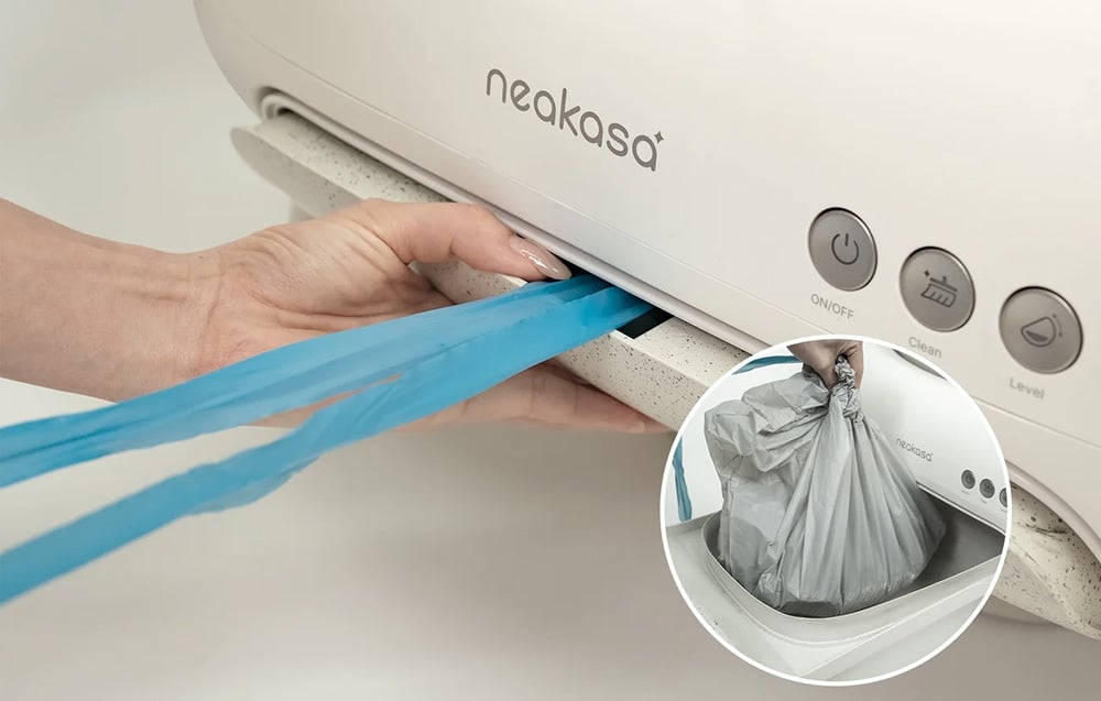 Ruka osoby vyťahuje modré vrecko z predného otvoru automatickej podstielky Neakasa, s vloženým obrázkom zauzleného vreca na odpadky