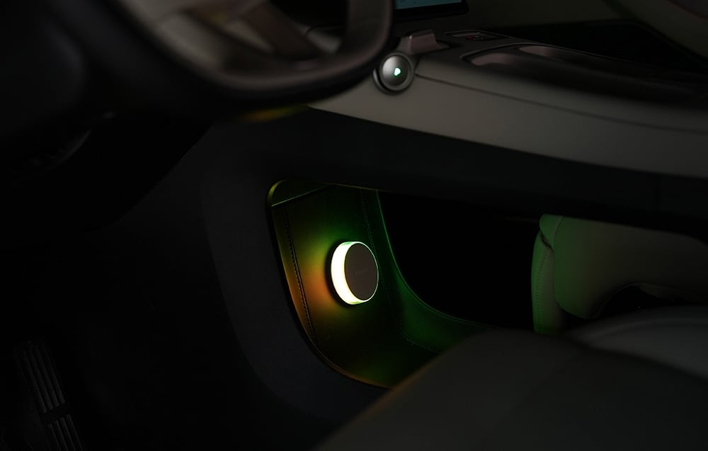 Nočná lampa Yeelight Vega namontovaná na spodnej časti palubnej dosky automobilu, osvetlená zelenožltým svetlom.