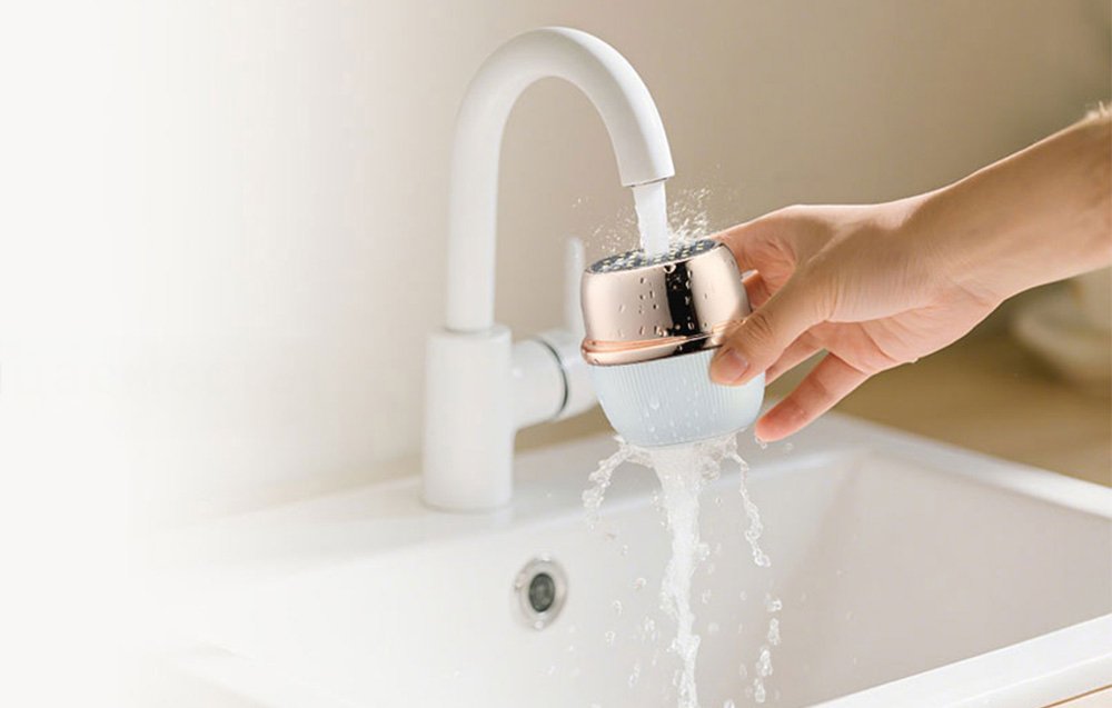 Zdvíhanie masážneho prístroja na tvár, ktorý sa čistí pod tečúcou vodou