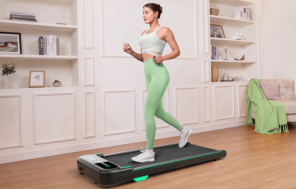 Žena so zviazanými vlasmi beží na bežiacom páse vo svetlej miestnosti.