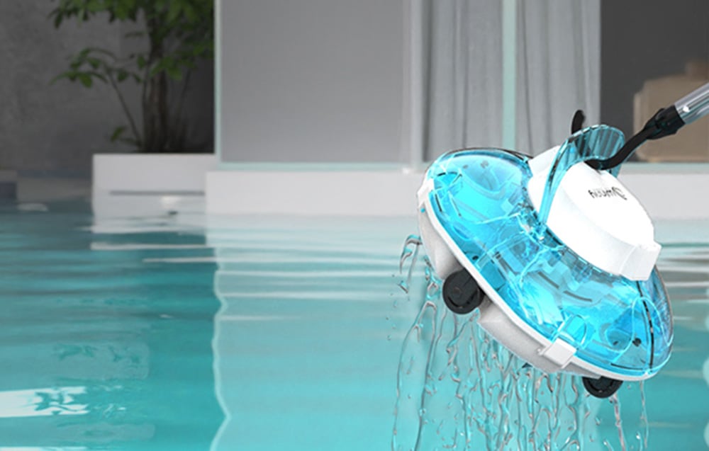 Biely bazénový robot s priehľadnou tyrkysovou kopulou je vytiahnutý z bazénu na okraji, z zariadenia kvapká voda