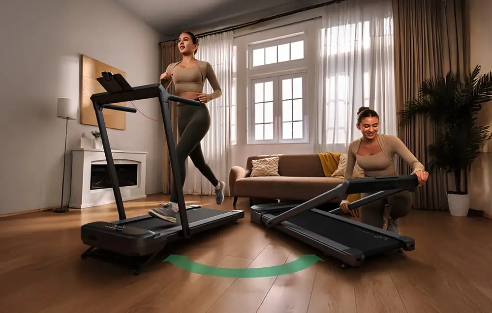 Dve ženy cvičia v obývačke, jedna beží na stacionárnom bežeckom páse, druhá skladá bežecký pás pod pohovku