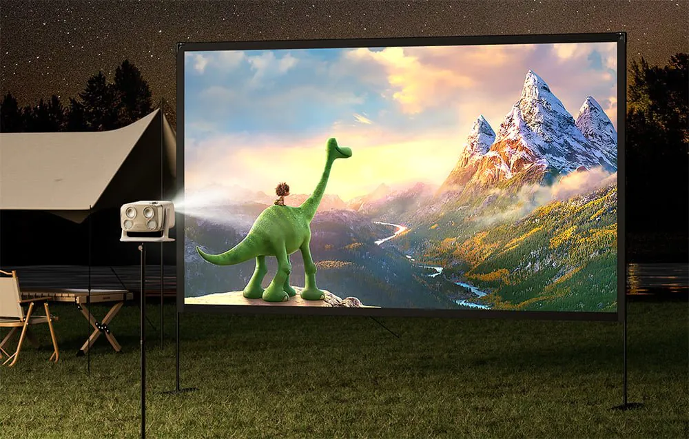 Vonkajšia premietacie plátno umiestnené na tráve vedľa stanu premieta animovanú horskú krajinu so zeleným dinosaurom.
